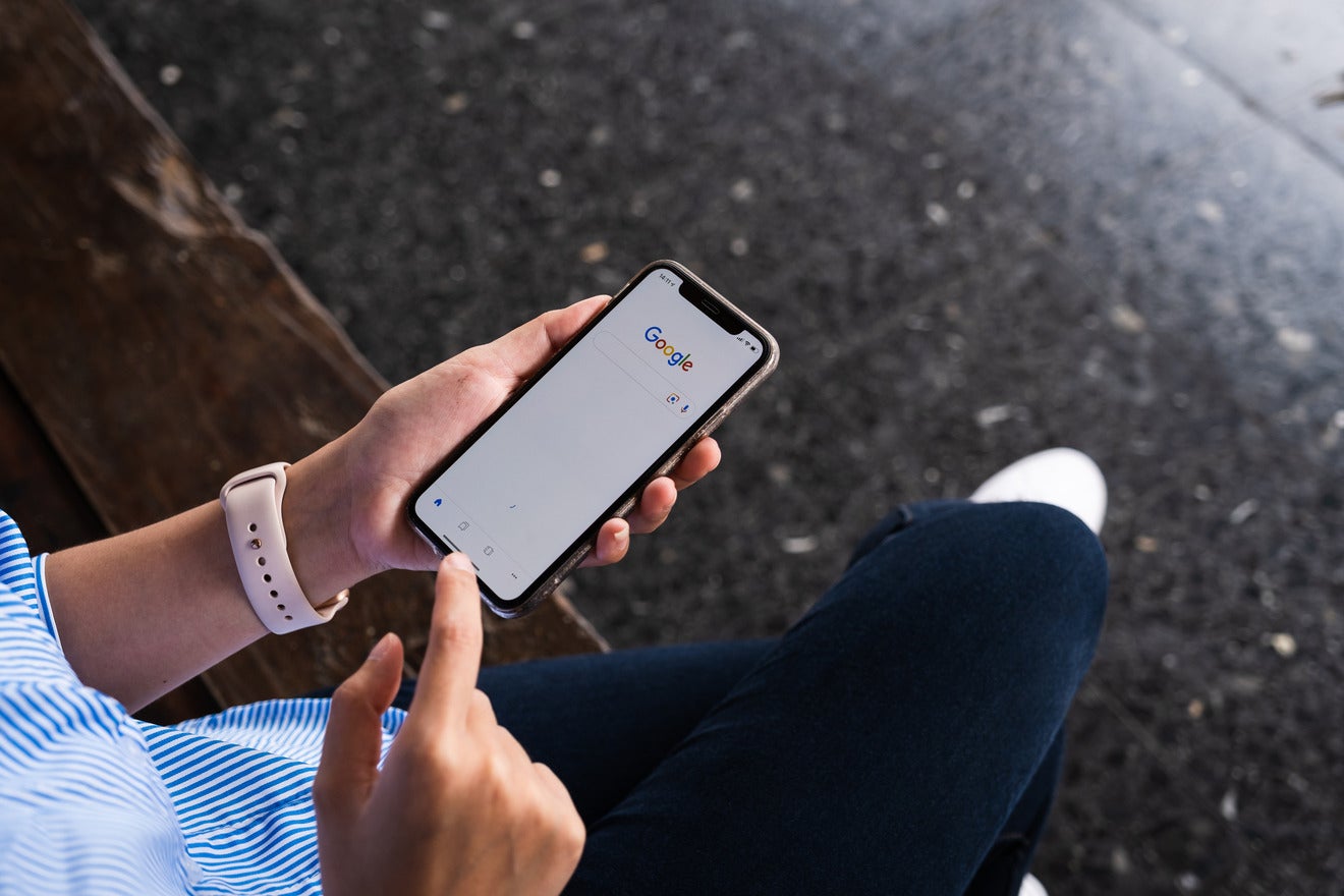 person using Google on phone while sat on a bench