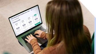 Woman using a laptop to complete an online purchase for a web builder with various prices displayed on her checkout screen