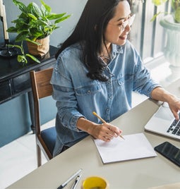 Woman working at a desk with a laptop and packages around her