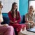 Three women in a casual business setting, engaging in conversation with a laptop on the table.