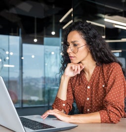 Businesswoman thinks while working on laptop in an office