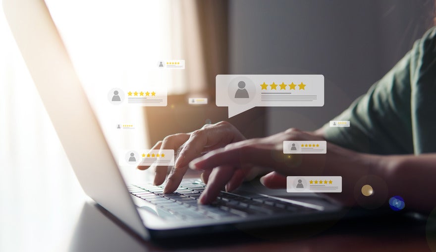 Person typing at a laptop with floating customer reviews around the hand