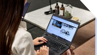 Woman in white shirt browsing her website content on a laptop in an office setting