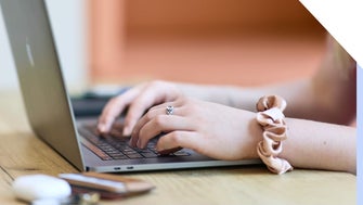 Close-up of a woman's hands typing on a laptop keyboard, showcasing productivity and technology use.