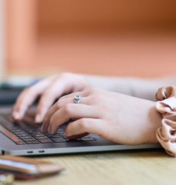 Close-up of a woman's hands typing on a laptop keyboard, showcasing productivity and technology use.