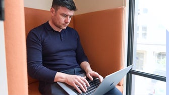 Man concentrates working and typing on his laptop in a modern office setting