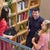 Colleagues engaging in a friendly conversation beside a bookshelf in an office environment