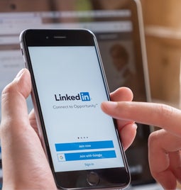 Person holding a mobile device with the LinkedIn login page on the screen