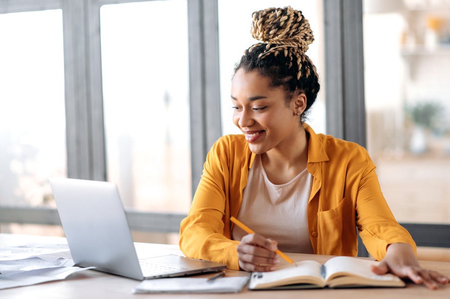 Woman working on a table and smiling at her laptop