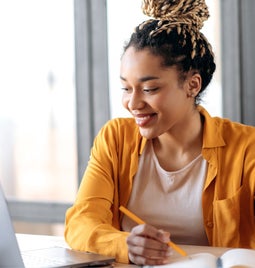 Woman working on a table and smiling at her laptop