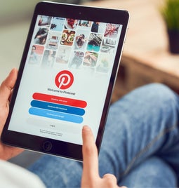 Person sat holding a tablet with the Pinterest login page on the screen