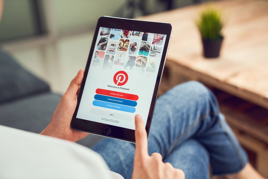 Person sat holding a tablet with the Pinterest login page on the screen