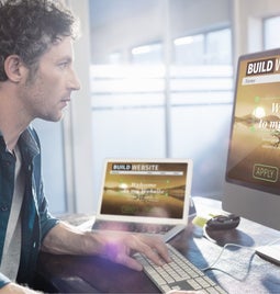 Man works at two screens building a website