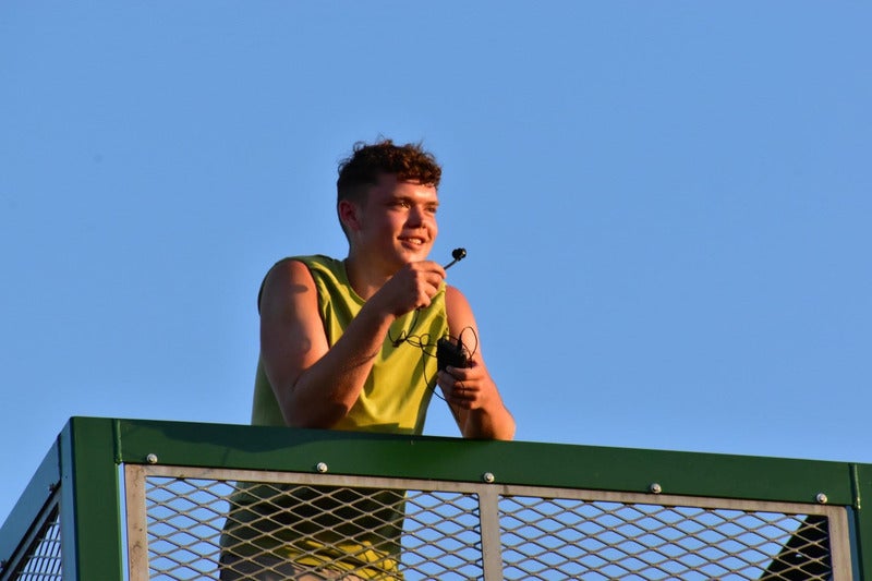 boy in yellow vest talking into microphone at sunset