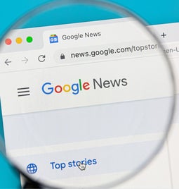 A magnifying glass zooming into the Google news webpage