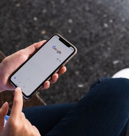 person using Google on phone while sat on a bench