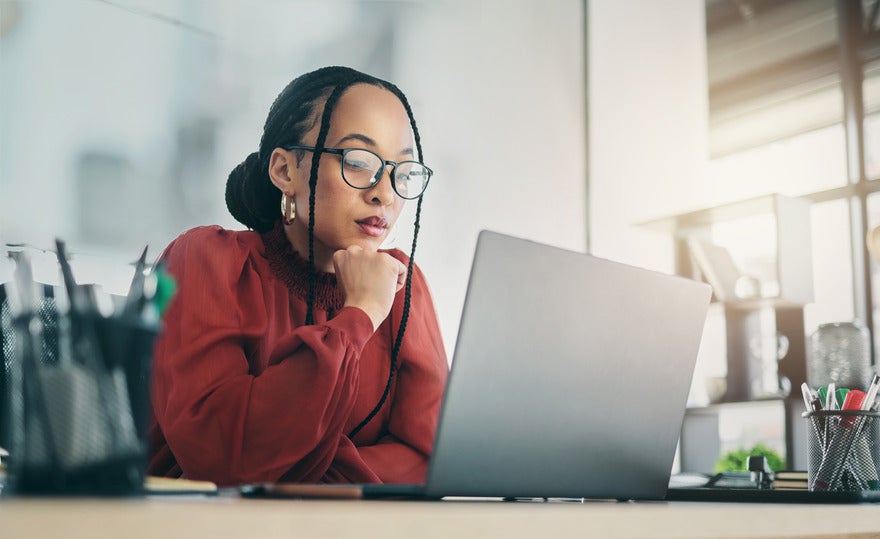 Woman sat and looking focused at the laptop in front of her