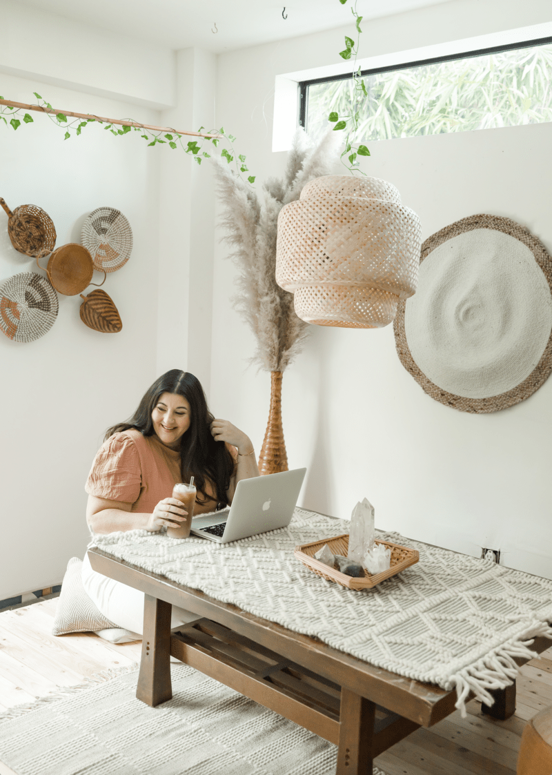 woman sitting in a nice, white and breezy apartment on a laptop